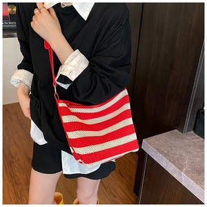 Detail of red and white striped woven tote bag with slim shoulder strap on model
