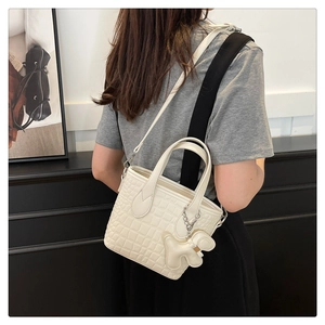 Detail of off-white crocodile embossed bucket bag with a cute heart charm on side