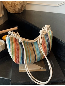 Colorful striped woven straw hobo bag with white knotted shoulder straps and vibrant design