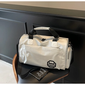 Détail du sac de voyage étanche argenté avec compartiment à chaussures séparé sur chaise