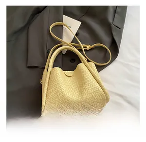 Gros plan d'un sac seau en cuir tressé jaune clair avec bandoulière amovible