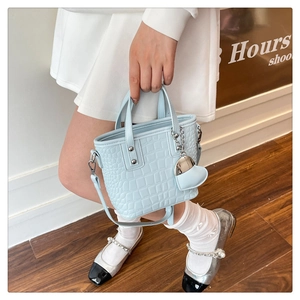 Detail of light blue croc-embossed bucket bag with silver studs and heart pendant