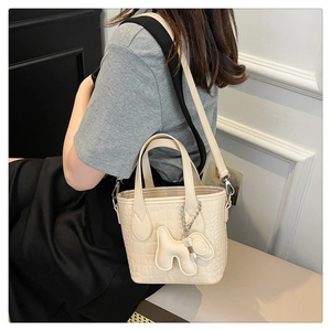 Detail of cream crocodile embossed bucket bag with a cute puppy charm and handles