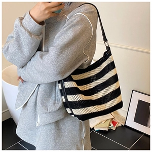 Detail of black and white striped knit tote bag with mesh texture and leather shoulder strap