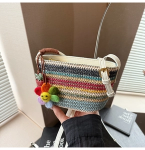 Détail du sac bandoulière en paille tressée colorée avec breloques fleurs et rayures