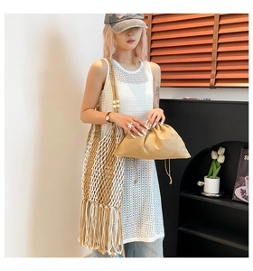 Detail of woven mesh beach tote bag featuring decorative tassels and wooden bead strap accents
