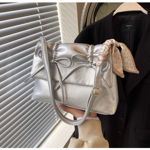 Détails du sac argenté métallisé avec nœuds papillon, texture plissée et foulard en soie