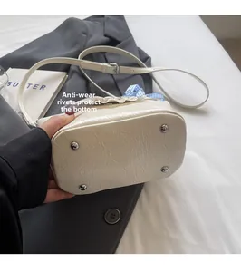 Detail view of mini bucket bag showing protective silver metal rivets on the bottom base