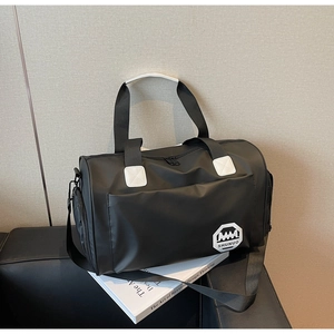 Détail du sac de voyage noir imperméable avec poignées renforcées et logo sur un canapé