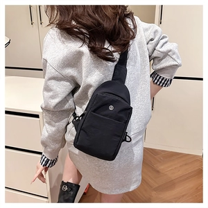 Rear view of black nylon crossbody chest bag worn by a model in a minimalist room