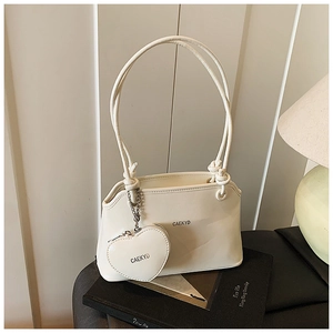 Détail d'un sac seau en cuir blanc avec porte-monnaie cœur amovible et bandoulière nouée