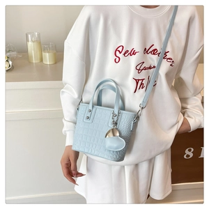 Detailed shot of light blue croc-embossed leather bucket bag with silver studs and heart charm
