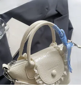 Detail of cream bucket bag with lace trim, ruffled faux leather and plaid ribbon handle