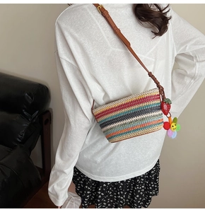 Détail du sac de plage tissé à rayures colorées avec breloques fraise et soleil