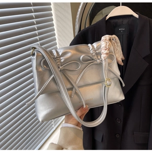 Détail du sac à main argenté matelassé avec texture bulle et foulard en soie imprimé