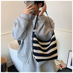 Detail of black and white striped knit tote bag with metal ring and shoulder strap