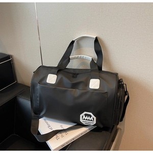 Détail du sac de voyage noir étanche avec coutures blanches sur un canapé en cuir