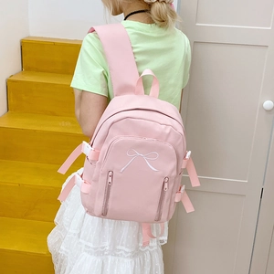 Détail du sac à dos en nylon rose clair avec broderie nœud blanc et boucles latérales