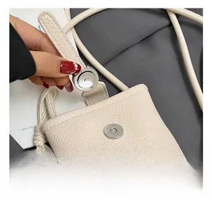 Détail du fermoir magnétique argenté et du cuir grainé du mini sac à bandoulière beige