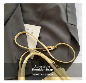 Détail macro de la bandoulière beige tressée avec boucle dorée réglable pour sac seau