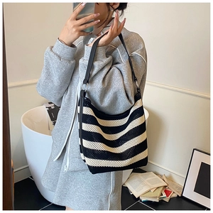 Lifestyle shot of black and white striped woven tote bag with leather shoulder straps