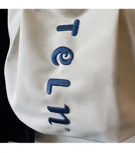 Detailed view of 3D navy blue embroidery on premium off-white canvas tote bag texture