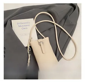 Détail d'un sac de téléphone en cuir crème avec boucle fer à cheval argentée et bandoulière