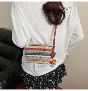 Détail d'un sac seau tressé coloré avec des breloques fruits et une bandoulière en cuir