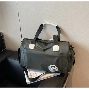Détail du sac de voyage vert armée imperméable sur un canapé avec le logo SHUNUO