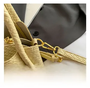 Vue détaillée de la texture tressée crème et des ferrures dorées sur le sac seau tendance
