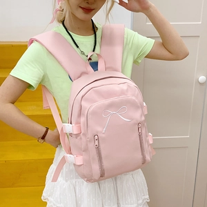 Détail du sac à dos rose avec broderie nœud blanc et boucles latérales sur mannequin