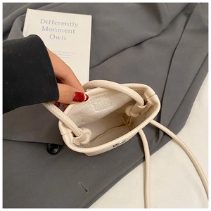 Detail view of the cream bucket bag interior with a sleek drawstring strap and micro lining