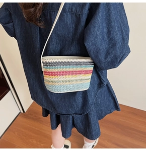 Détail d'un sac bandoulière en paille à rayures arc-en-ciel et bandoulière blanche