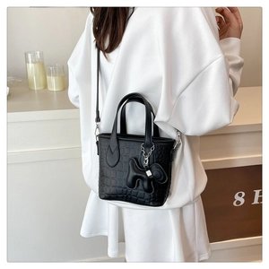 Detail of black crocodile texture mini tote bag with cute dog charm on side