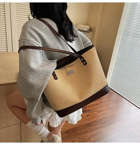 Detailed view of model carrying the large woven straw tote bag with brown leather straps