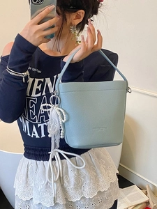Borsa a secchiello azzurra motivo litchi con ciondolo di perle portata da modella