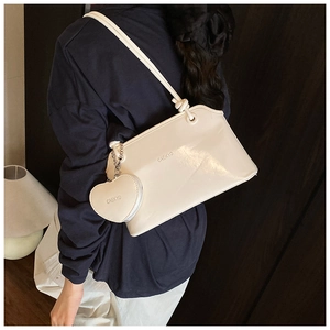 Détail du sac seau blanc crème avec un charm porte-monnaie amovible en forme de cœur