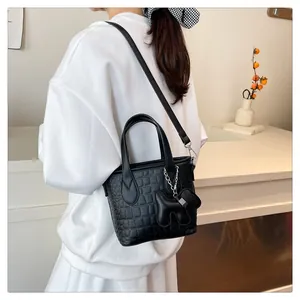 Detail of black crocodile texture bucket bag with a dog charm and adjustable strap
