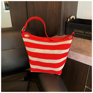 Detail of red and white striped woven tote bag with red leather straps on a chair