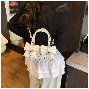 Vue détaillée d'un sac à main blanc à pois avec nœuds 3D porté par un mannequin femme