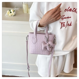 Detail of light purple crocodile embossed mini tote bag with cute dog charm accessory