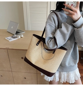Detailed view of woven straw tote bag with brown leather base and metallic logo accents