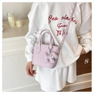 Detail view of lavender bucket bag with crocodile texture and dog-shaped leather charm
