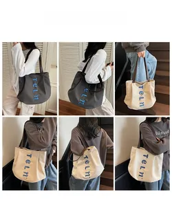 Detail view of large canvas tote bag with embroidered letters in grey and cream white colors