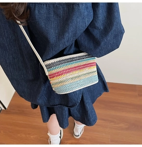 Détail d'un sac en paille tissé à rayures arc-en-ciel avec texture fine et bandoulière blanche