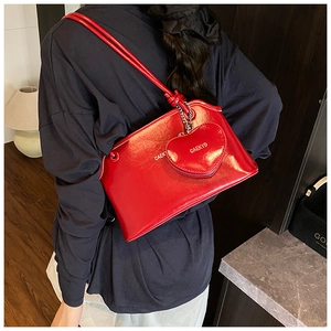 Détail d'un sac seau en cuir verni rouge avec un porte-monnaie assorti en forme de cœur