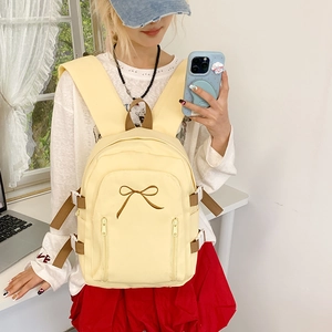 Détail du sac à dos en toile jaune avec broderie nœud marron et poches zippées