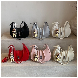 Close-up of six colorful textured leather dumpling bags with pearl doll charms on a stone step