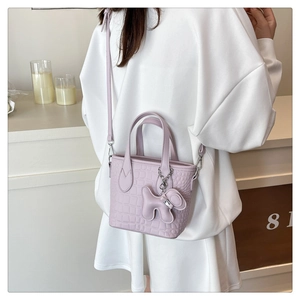 Detail of light purple crocodile texture tote bag with a cute dog charm on model back