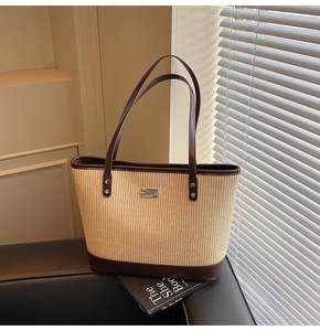 Detail of the woven tote bag showing beige straw texture and brown leather trim accents